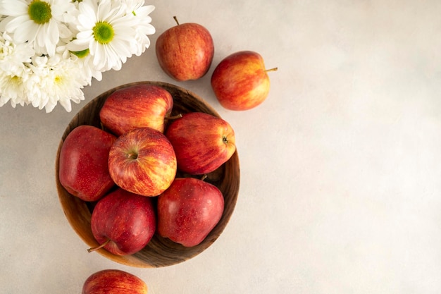 Красные яблоки в миске на деревянном деревенском фоне свежие красные яблочные фрукты с цветами вид сверху
