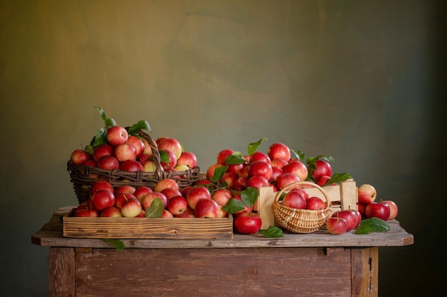 Red apples on old wooden table on background green wall