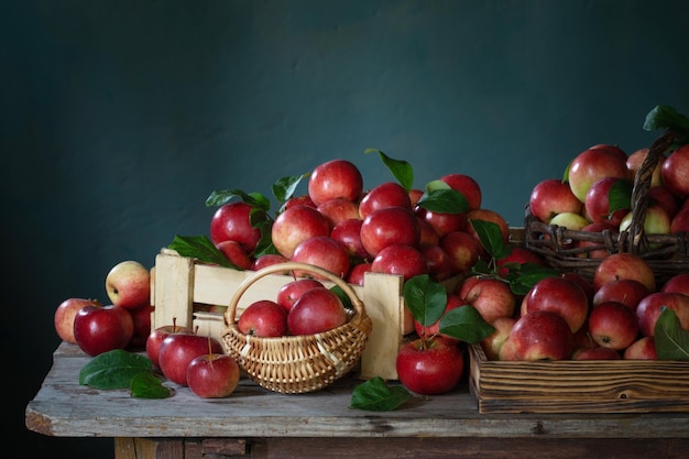 Red apples on old wooden table on background green wall