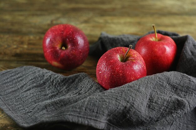 The red apples were washed and placed on a wooden table. There is a towel next to it