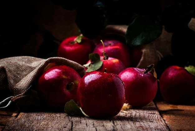 Red apples with drops on vintage wooden background selective focus