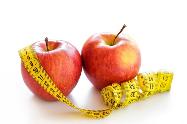 Red apples with measuring tape isolated on white Healthy lifestyle diet concept Closeup