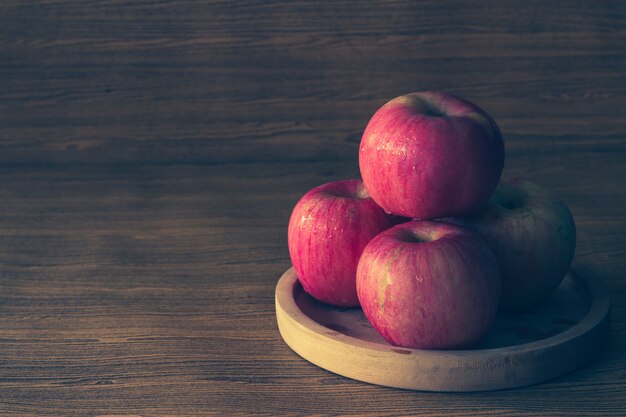 Red apples on the wooden table background.