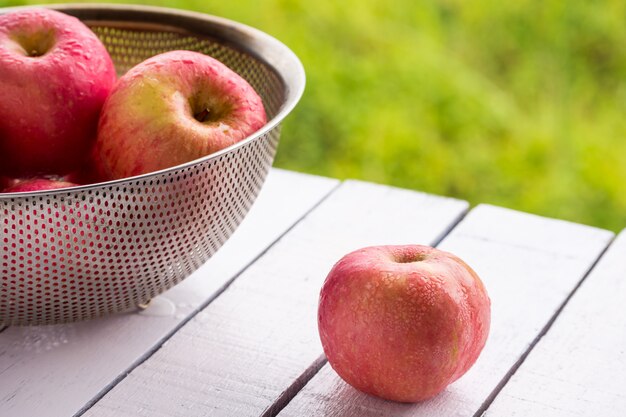 Red apples on wooden table with natural green background