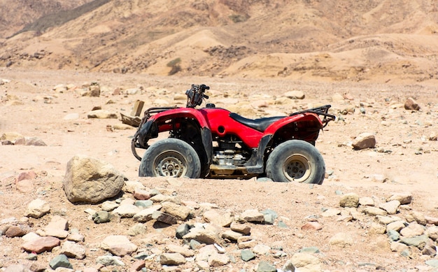 エジプトの砂漠の石の背景に赤いATV