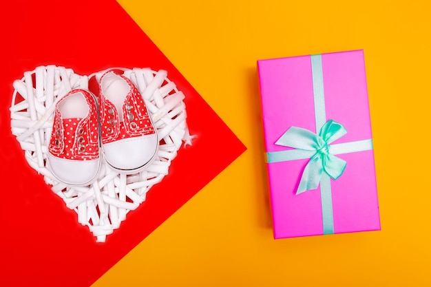 Red baby shoes with white polka dots on a red background with gifts