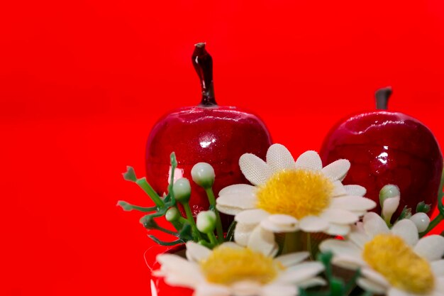 A red background with a bunch of flowers and a red apple.