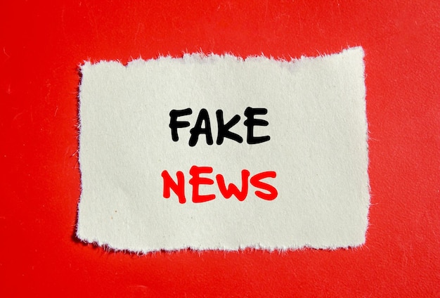 красный фон с белой бумагой, на которой написано "фальшивые новости"