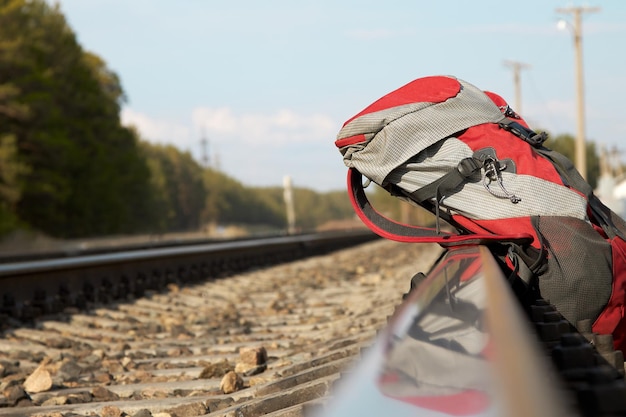 Red backpack at the railway in the pine forest travel concept