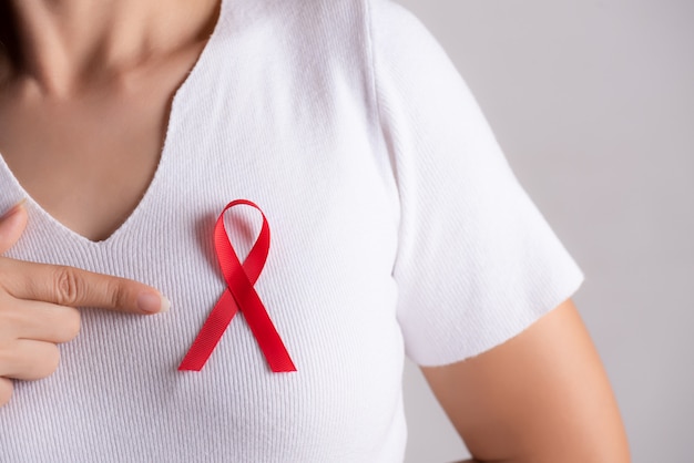 Nastro distintivo rosso sul petto della donna per sostenere l'aids day. concetto di assistenza sanitaria.