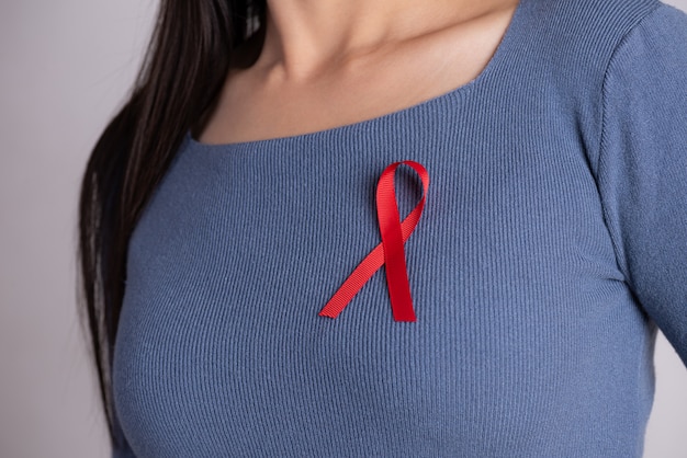 Red badge ribbon on woman chest to support AIDS Day. Healthcare .