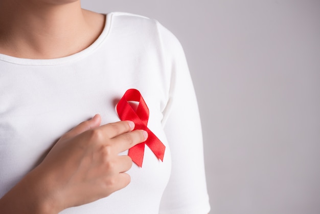 Red badge ribbon on woman chest to support AIDS Day. 