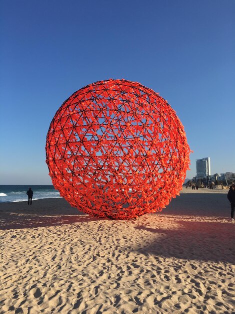 Foto palla rossa sulla spiaggia contro un cielo blu limpido