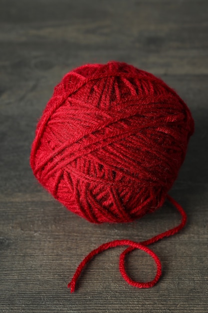 Red ball of yarn on gray wooden background..