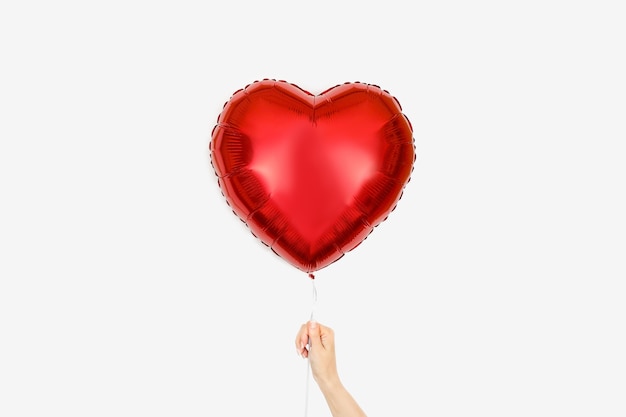 Red Balloon of heart shaped foil on white in girls hand Valentines Day or wedding party decoration