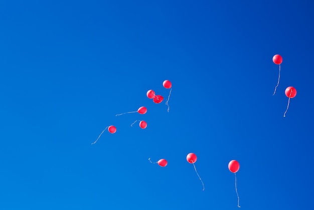 Red balloons flying on the blue sky