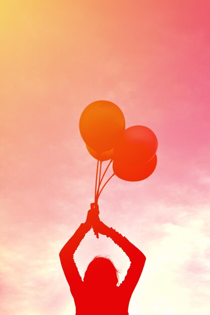 Photo red balloons hanging against orange sky