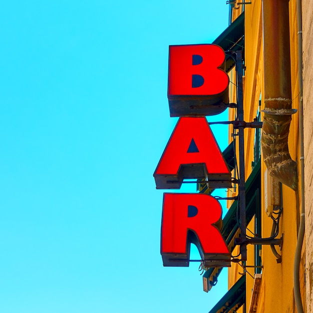 Red bar sign ion the wall against the blue sky