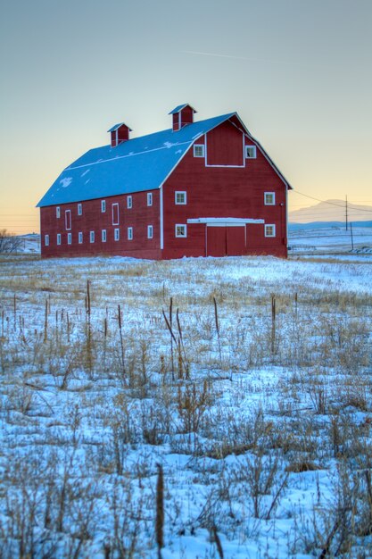 Красный сарай на поле, засыпанном снегом.