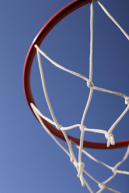 A red basketball hoop with a white net against a blue cloudless sky