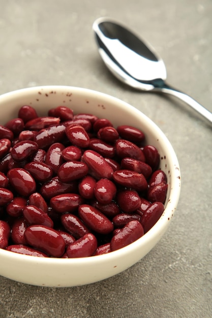 Red beans in bowl and spoon on grey background