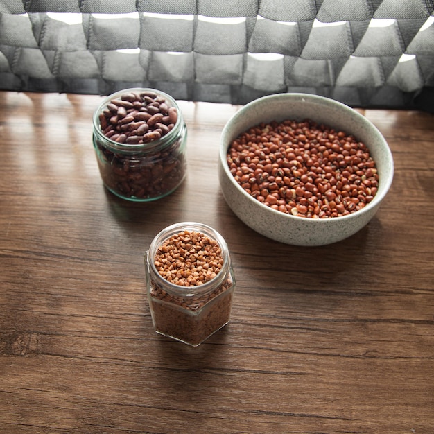 Red beans and buckwheat in bowls on wooden table.