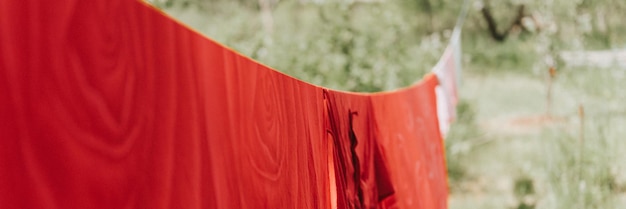 Foto la biancheria da letto rossa è asciugata sul filo da bucato sulla strada nel cortile della casa di campagna della famiglia del villaggio