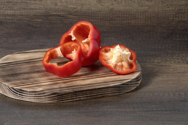 Red bell pepper cut into three pieces on a cutting board