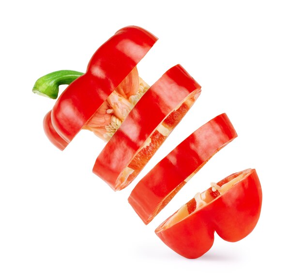 Red bell pepper sliced into pieces in the air on an isolated white background