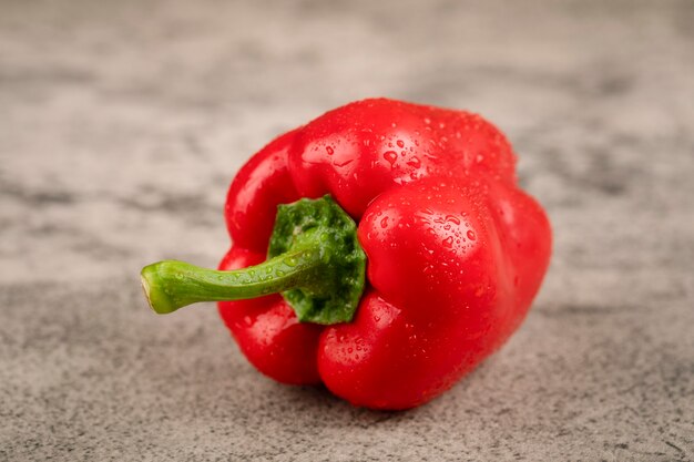 Red bell pepper with water drops on stone surface