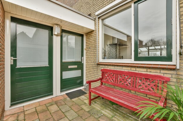 A red bench in front of a house with green