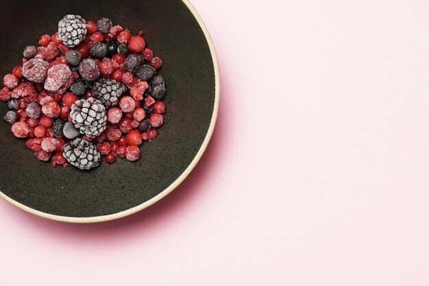 Red berries and black berries on a black plate  flat lay