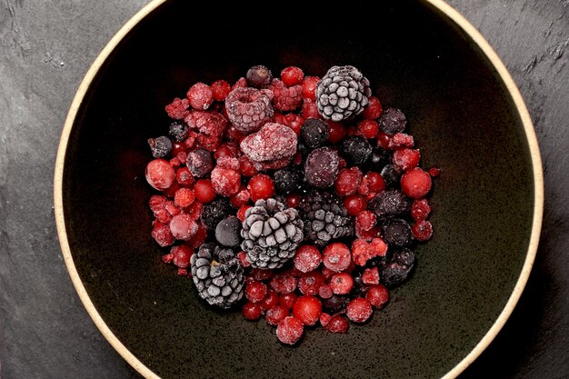 Red berries and black berries on a black plate flat lay