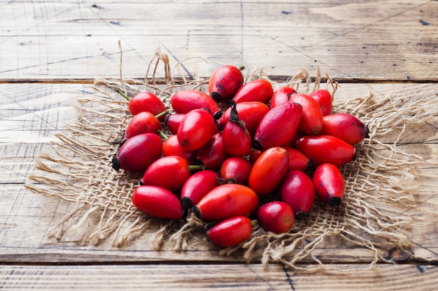 Red berries rosehip fruit on a wooden background. Copy space.