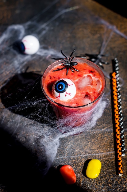 Foto cocktail ai frutti rossi con ghiaccio, occhi e ragni per la festa di halloween con il web