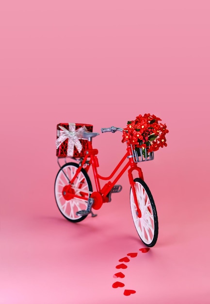 Photo red bicycle with gift box and bouquet of flowers in a basket. valentine's day and romantic concept, transportation, eco and love