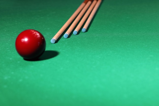 Red billiard ball and cues on table Space for text