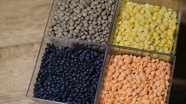 Photo red, black, brown and peeled lentils in a crystal glasses on a rustic wooden background