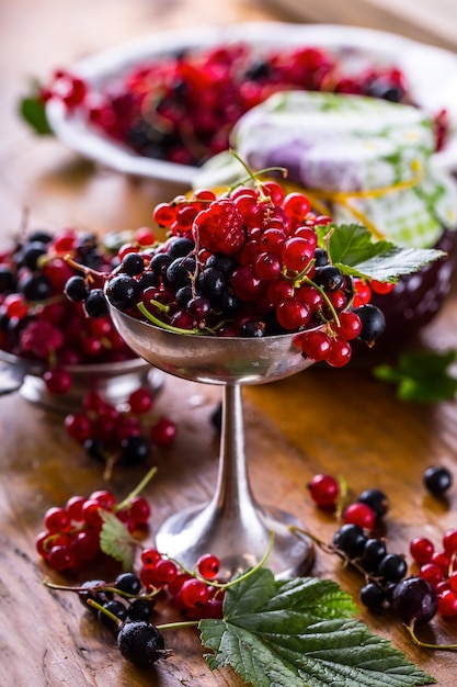 Red and black currant in rustic bowl on kitchen table.