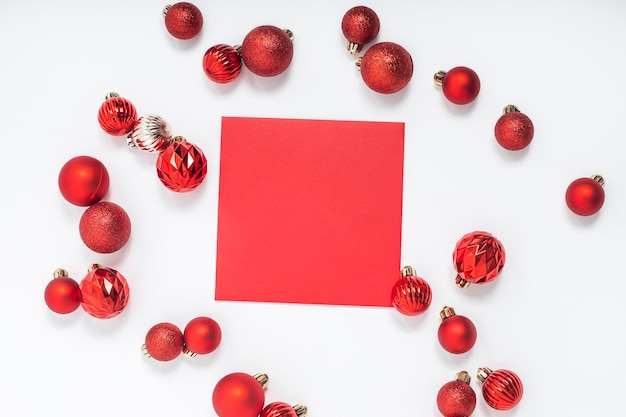 Red blank paper and decorative balls on a white background. Top view, flat lay.