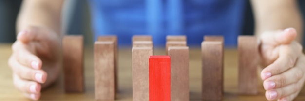 Photo red block standing on table in front of wooden ones near female hands closeup business