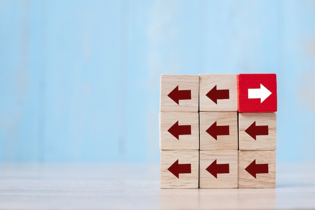 Red block with different direction of arrow on table. 