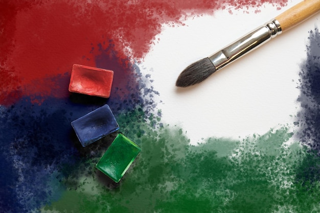 사진 빨강, 파랑 및 녹색 수채색 용기, 여러 가지 빛깔의 얼룩 배경에 있는 아트 브러시.