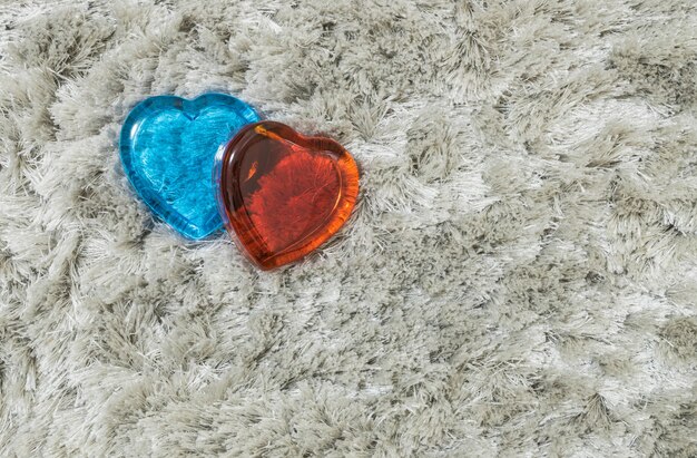 red and blue glass in heart shape on gray carpet 