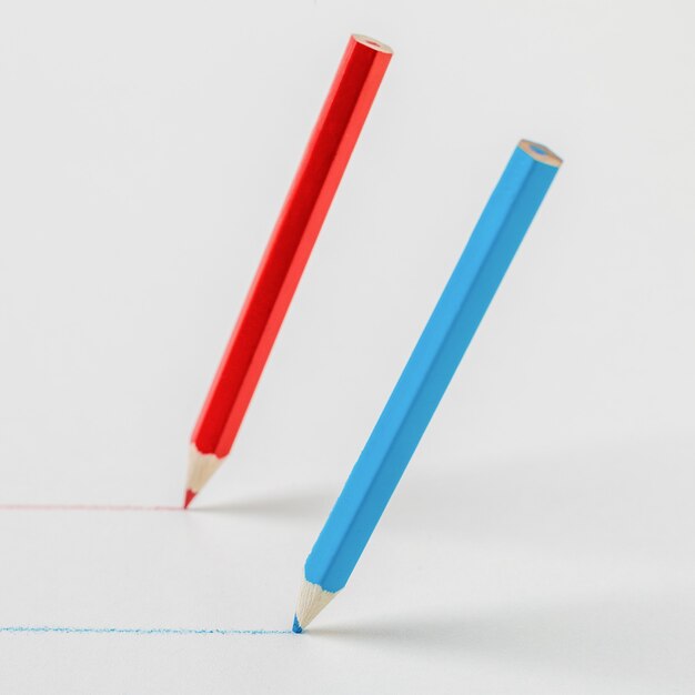 Red and blue pencils drawing parallel lines. The concept of cooperation.