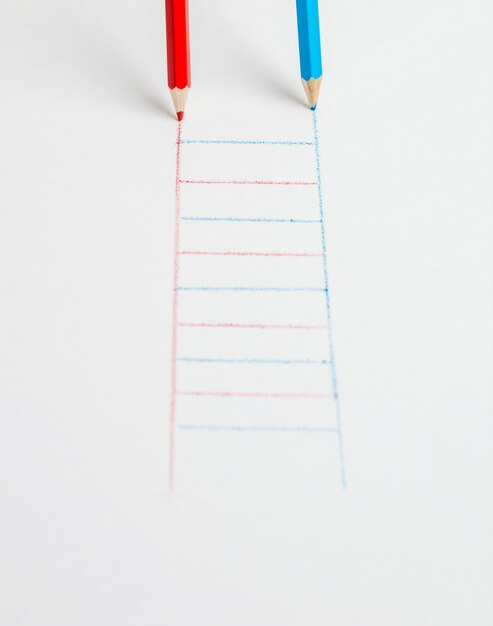 Red and blue pencils drawing a staircase on a white surface. The concept of development.