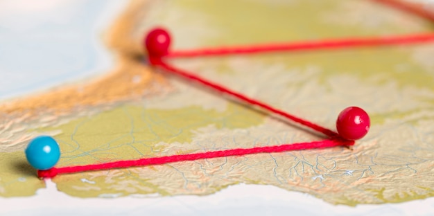 Red and blue pushpins with thread on route map