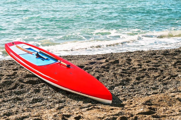 Tabellone rosso per stand up paddle surf (sup) sulla spiaggia del mare