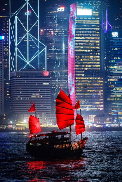 Red boat in river against illuminated buildings at night