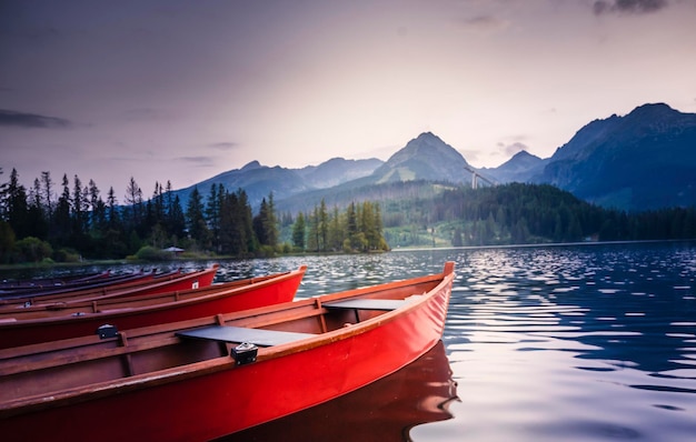 Red boats on lake strbske pleso morning view of the high tatras national park slovakia europe